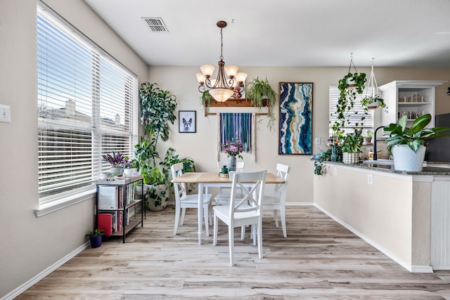 dining room featuring visible vents, baseboards, an inviting chandelier, and wood finished floors