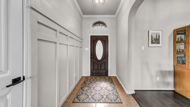 entryway featuring arched walkways, dark tile patterned flooring, baseboards, and ornamental molding