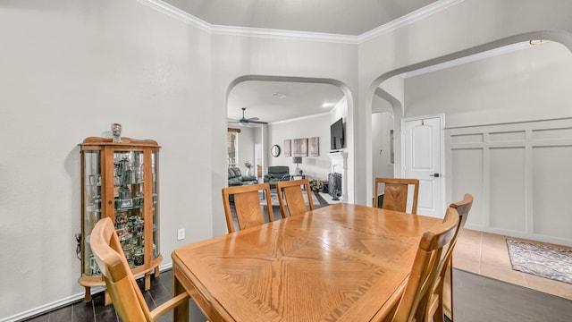 dining room with a decorative wall, arched walkways, and ornamental molding