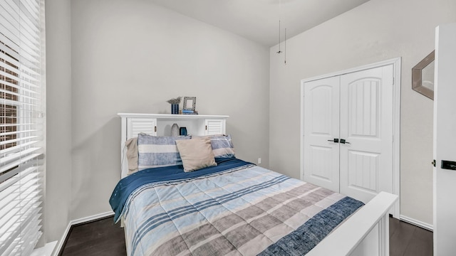 bedroom with a closet, baseboards, and dark wood-type flooring