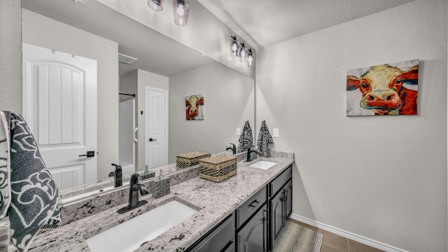 full bath featuring a sink, baseboards, and double vanity