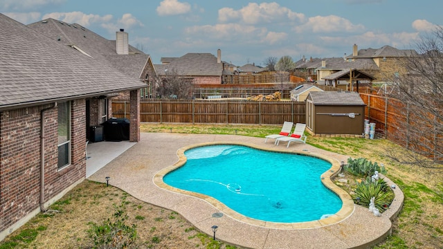 view of pool with a fenced backyard, an outdoor structure, a storage shed, and a patio