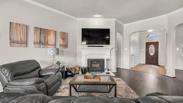 living room featuring baseboards, ornamental molding, a fireplace, hardwood / wood-style flooring, and arched walkways