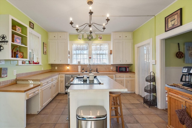 kitchen with backsplash, a center island, a sink, light countertops, and a chandelier