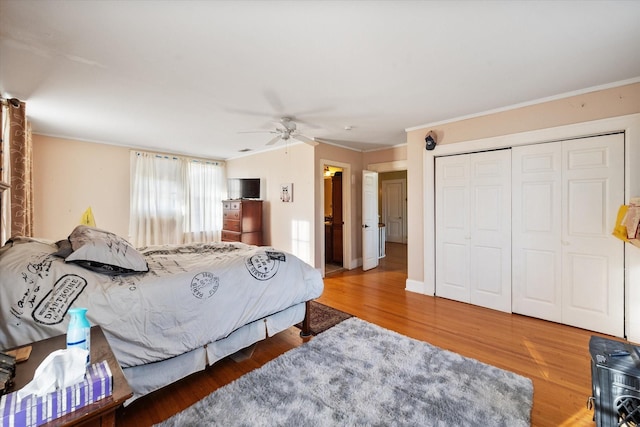 bedroom with ceiling fan, ornamental molding, a closet, and wood finished floors