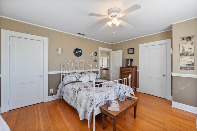 bedroom with ceiling fan, visible vents, crown molding, light wood-type flooring, and baseboards