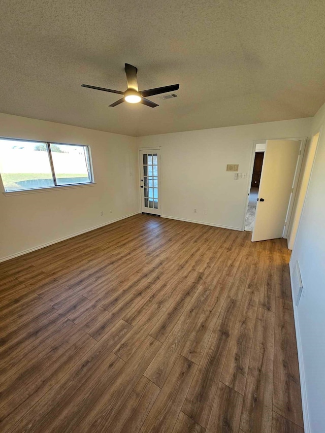 unfurnished room featuring visible vents, a textured ceiling, dark wood-type flooring, and ceiling fan