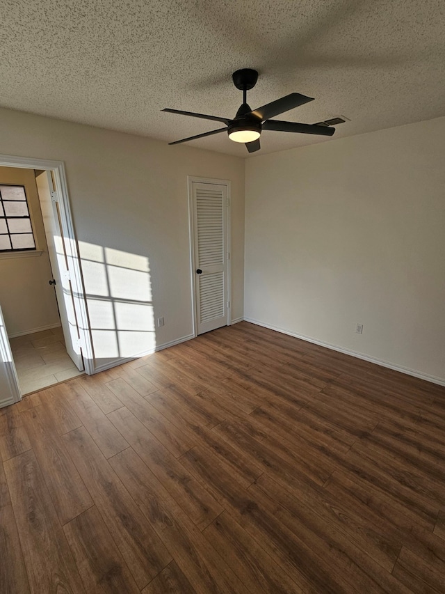 unfurnished bedroom with a closet, visible vents, a textured ceiling, and wood finished floors