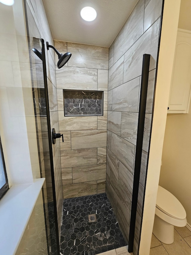 bathroom with tile patterned flooring, toilet, and a stall shower