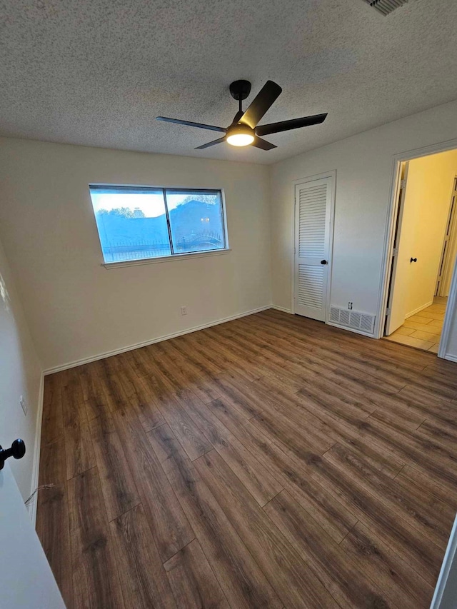 unfurnished bedroom featuring visible vents, a textured ceiling, and wood finished floors