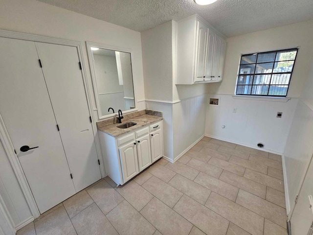 laundry room with electric dryer hookup, a wainscoted wall, washer hookup, a sink, and cabinet space