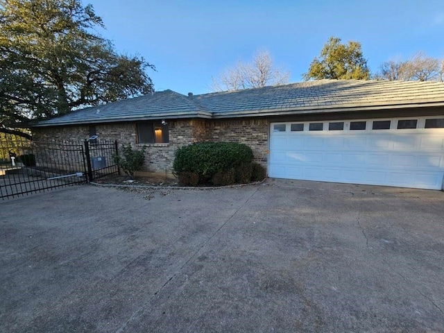 ranch-style house featuring concrete driveway, a gate, fence, and a garage