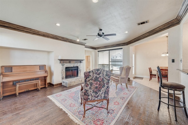 living area featuring visible vents, ceiling fan with notable chandelier, a fireplace, and baseboards