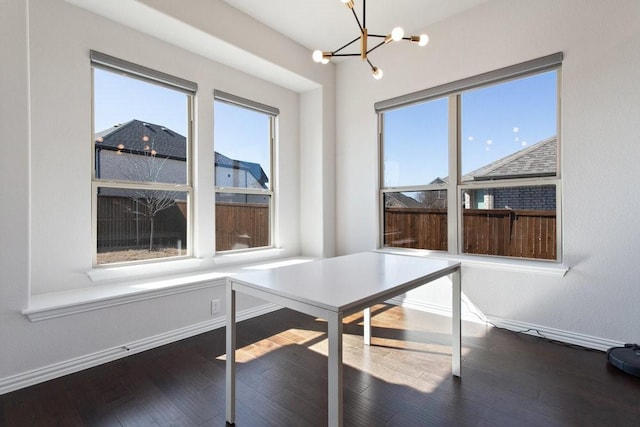 unfurnished dining area with baseboards, dark wood-type flooring, and a notable chandelier