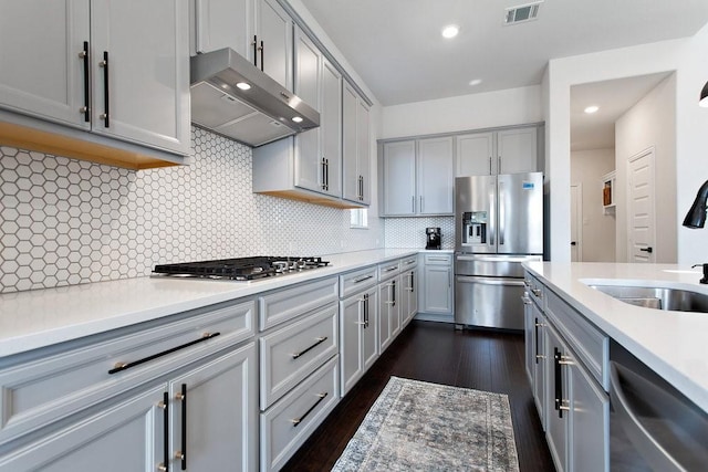 kitchen featuring a sink, wall chimney exhaust hood, gray cabinets, and stainless steel appliances