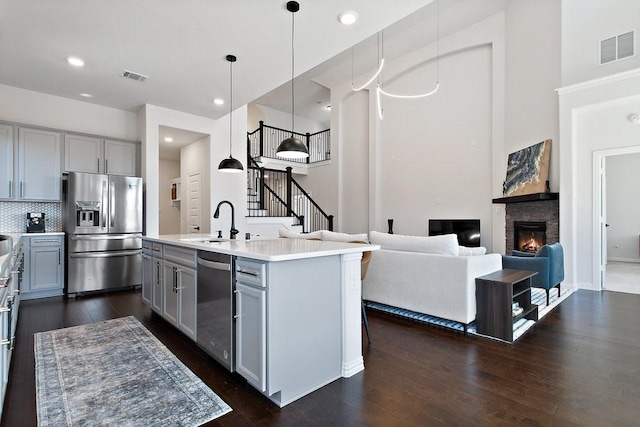 kitchen featuring visible vents, gray cabinets, a sink, appliances with stainless steel finishes, and dark wood-style flooring