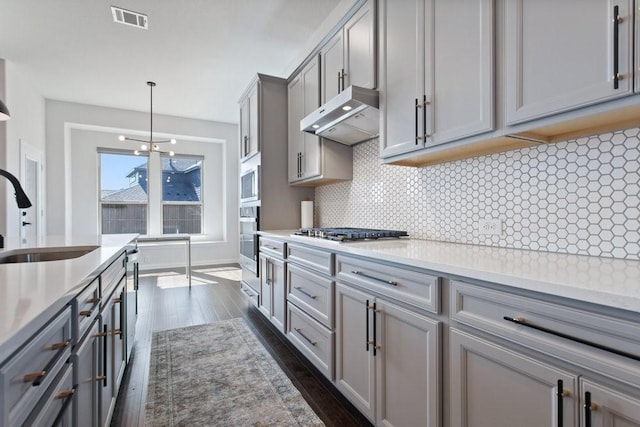 kitchen with visible vents, gray cabinets, a sink, stainless steel appliances, and under cabinet range hood