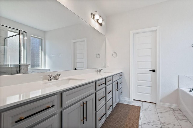 full bath featuring marble finish floor, a sink, double vanity, baseboards, and a bath