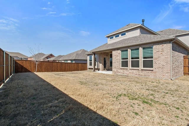 back of house featuring a patio, a fenced backyard, brick siding, and a shingled roof