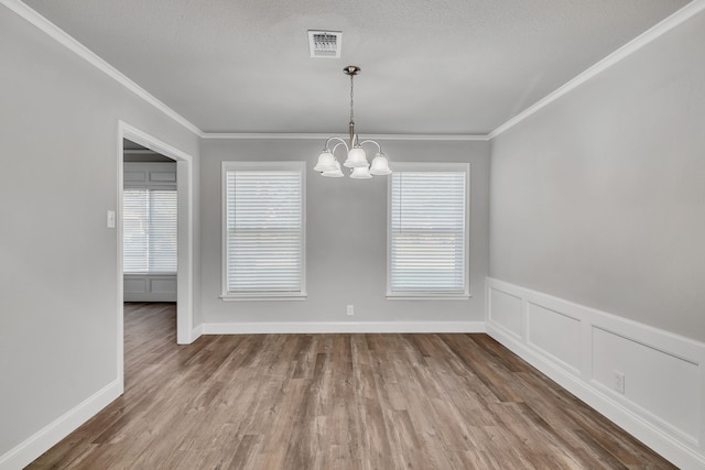 unfurnished dining area featuring a healthy amount of sunlight, wood finished floors, visible vents, and a chandelier