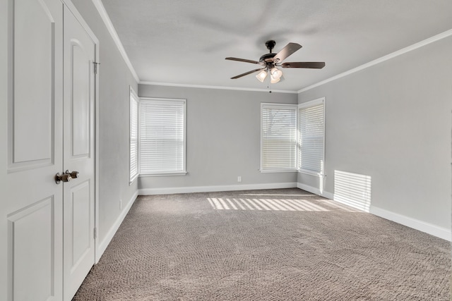 carpeted empty room with ceiling fan, baseboards, and ornamental molding