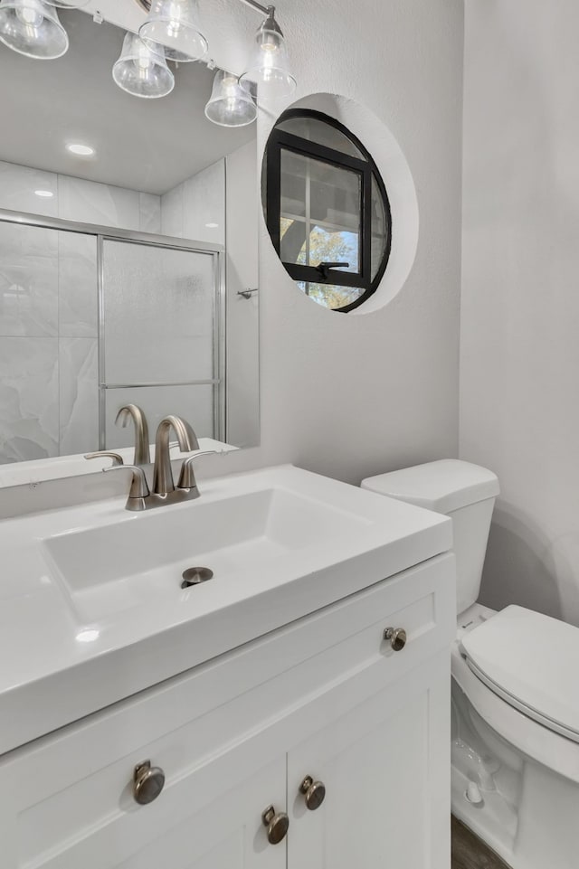 bathroom featuring vanity, toilet, and a stall shower