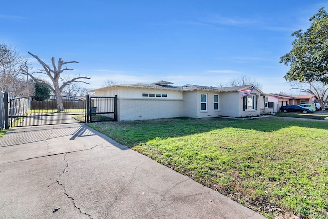 view of side of property with a gate, fence, driveway, a yard, and brick siding