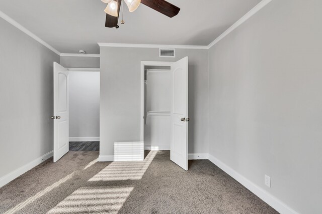 unfurnished bedroom with visible vents, crown molding, ceiling fan, baseboards, and carpet