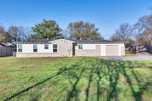 view of front of house featuring board and batten siding, driveway, a front lawn, and fence