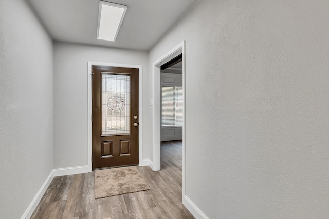 entrance foyer featuring a textured wall, baseboards, and wood finished floors