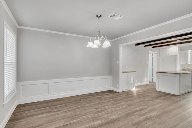 spare room with an inviting chandelier, light wood-style flooring, crown molding, and visible vents