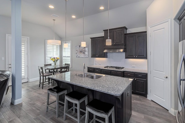 4152 Sanders Dr, Celina, TX 75009 - kitchen with a sink, under cabinet range hood, appliances with stainless steel finishes, a breakfast bar area, and vaulted ceiling