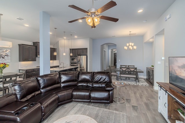 4152 Sanders Dr, Celina, TX 75009 - living room featuring light wood finished floors, visible vents, ceiling fan with notable chandelier, recessed lighting, and arched walkways