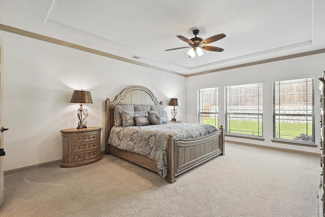 bedroom featuring light colored carpet, a ceiling fan, a tray ceiling, and ornamental molding