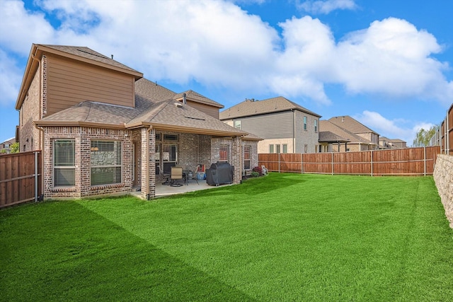 rear view of property featuring a patio area, a fenced backyard, and a shingled roof