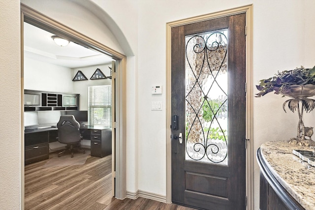 foyer featuring baseboards, built in desk, and dark wood-style flooring