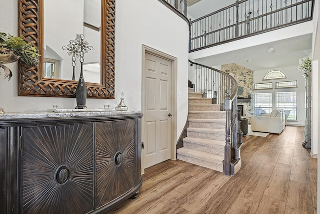 stairway with indoor bar, wood-type flooring, and a high ceiling