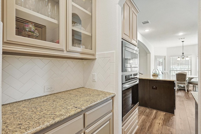 6015 Liverpool St, Celina, TX 76227 - kitchen with appliances with stainless steel finishes, cream cabinets, backsplash, light wood-type flooring, and glass insert cabinets