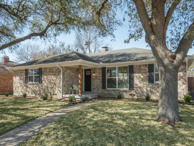 ranch-style home featuring a front yard, a porch, brick siding, and a chimney