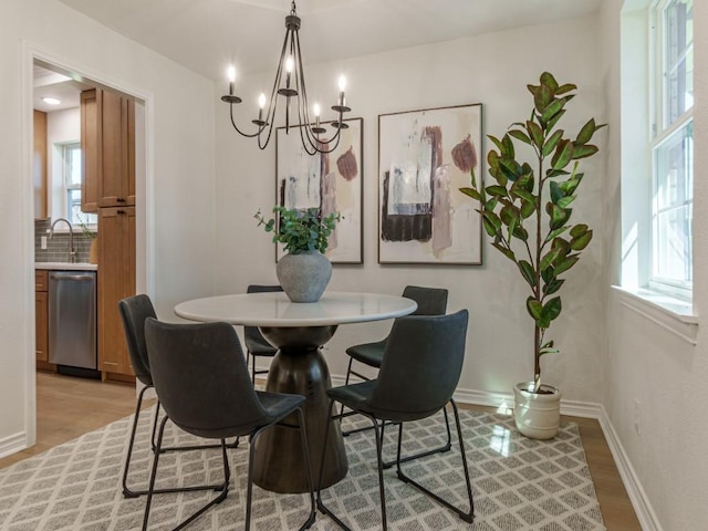 dining room featuring a notable chandelier, baseboards, and light wood-type flooring