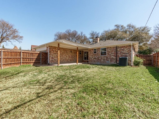 rear view of house with brick siding, a fenced backyard, a lawn, and central AC