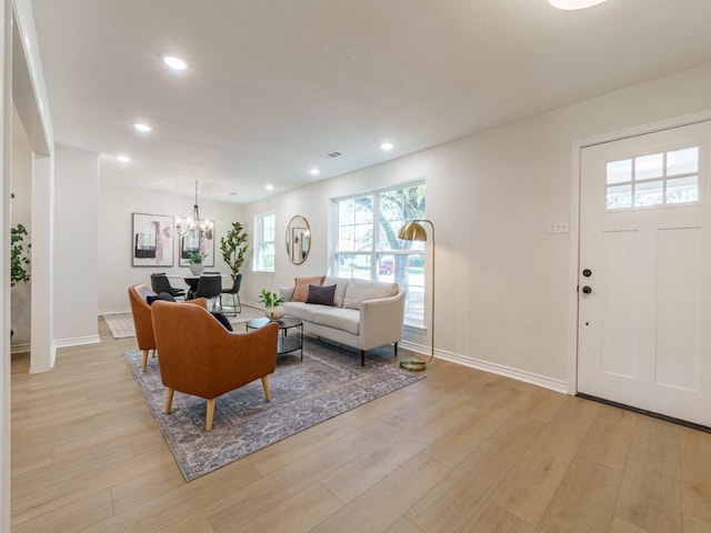 living room featuring recessed lighting, baseboards, a notable chandelier, and light wood finished floors