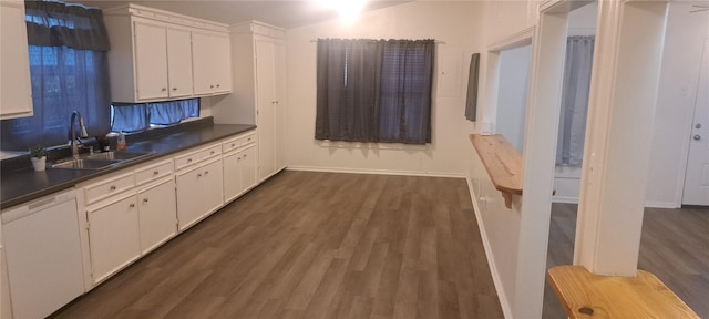 kitchen with dark wood-style floors, a sink, white cabinets, dishwasher, and dark countertops