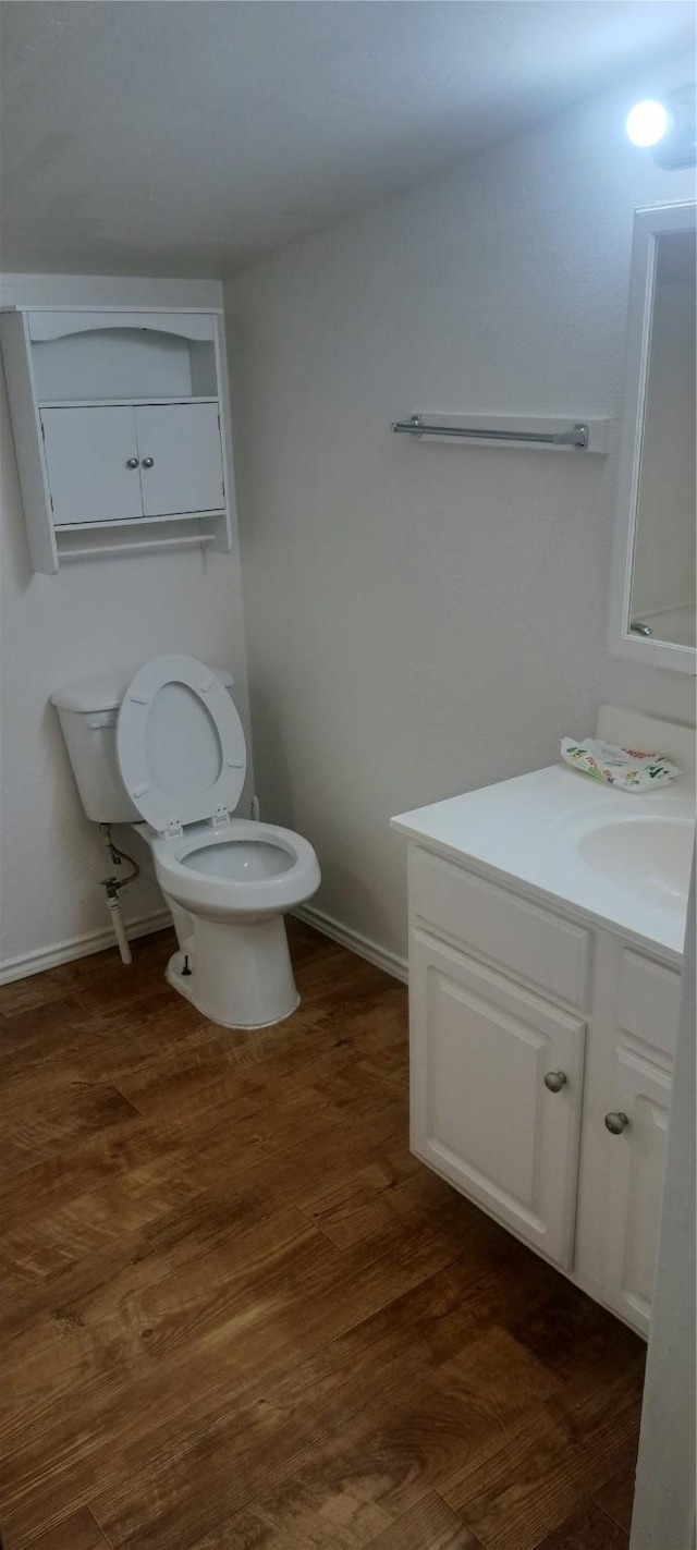 bathroom with toilet, vanity, baseboards, and wood finished floors