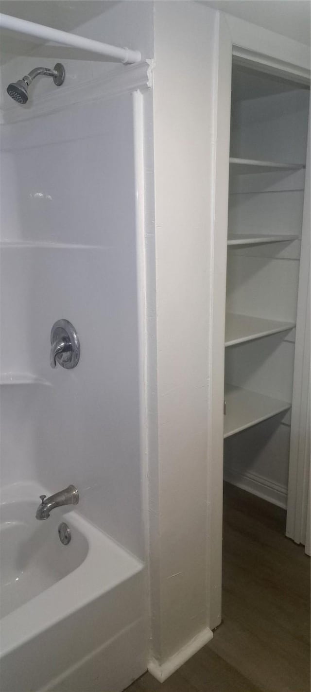 bathroom with shower / washtub combination and wood finished floors