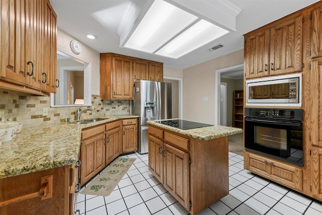 kitchen with visible vents, a center island, light tile patterned flooring, black appliances, and a sink