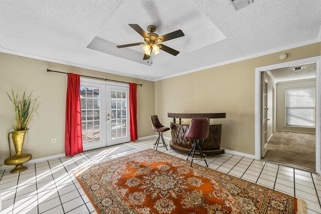 living area with tile patterned flooring, french doors, a wealth of natural light, and a tray ceiling