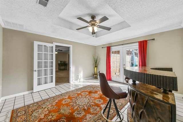 office space featuring a tray ceiling, ornamental molding, ceiling fan, french doors, and tile patterned floors