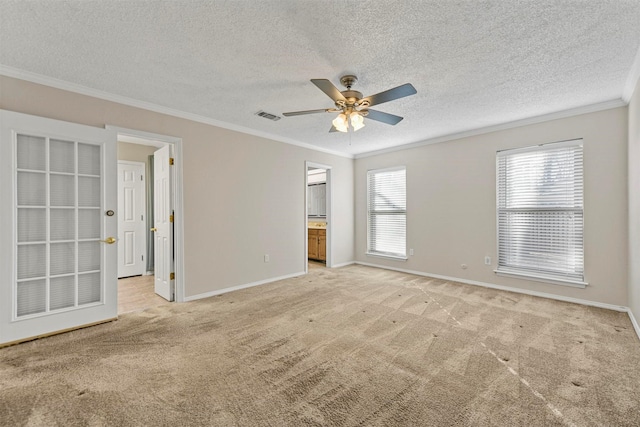 carpeted empty room with visible vents, baseboards, ceiling fan, and crown molding