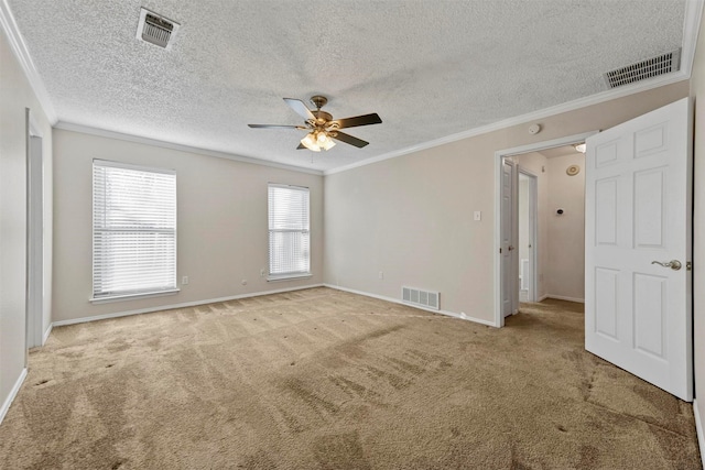 carpeted empty room with visible vents, a ceiling fan, and crown molding